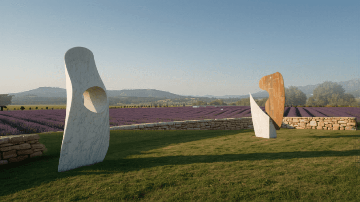 Visiteurs découvrant des sculptures contemporaines dans un jardin provençal ensoleillé au printemps